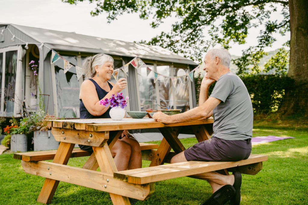 Two people cheering on a bench outside their caravan | Hillandale | Case Study | Reech