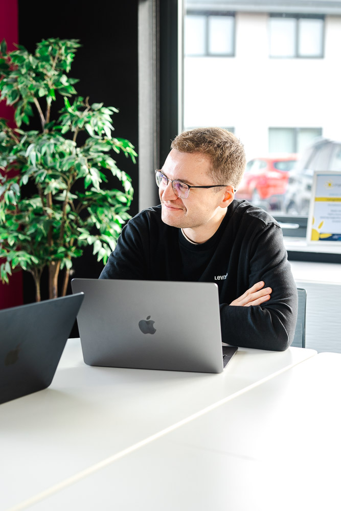 Huw sitting in the meeting room listening to another employee | Reech