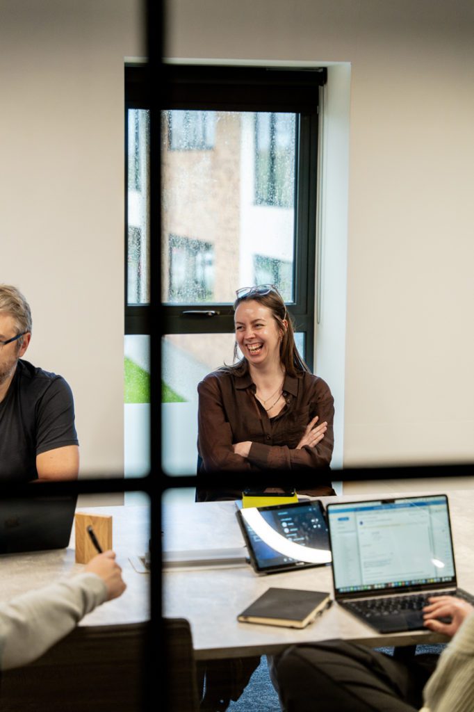 Marketer smiling while discussing project with team - Reech Agency