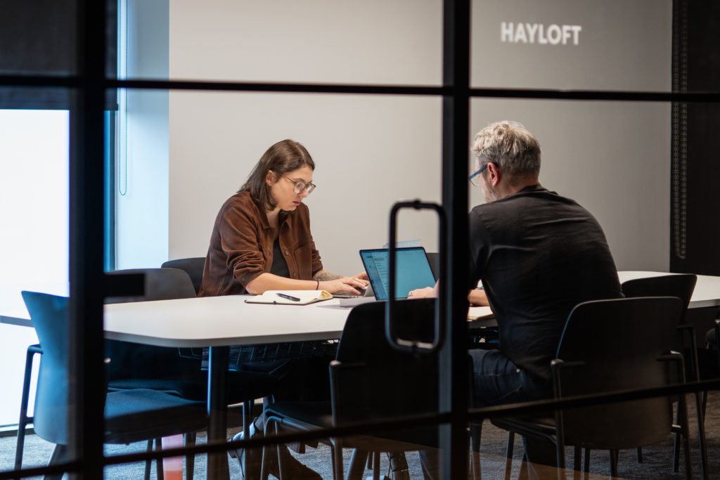 Marketing specialists collaborating on a digital advertising strategy using laptops in a meeting space.