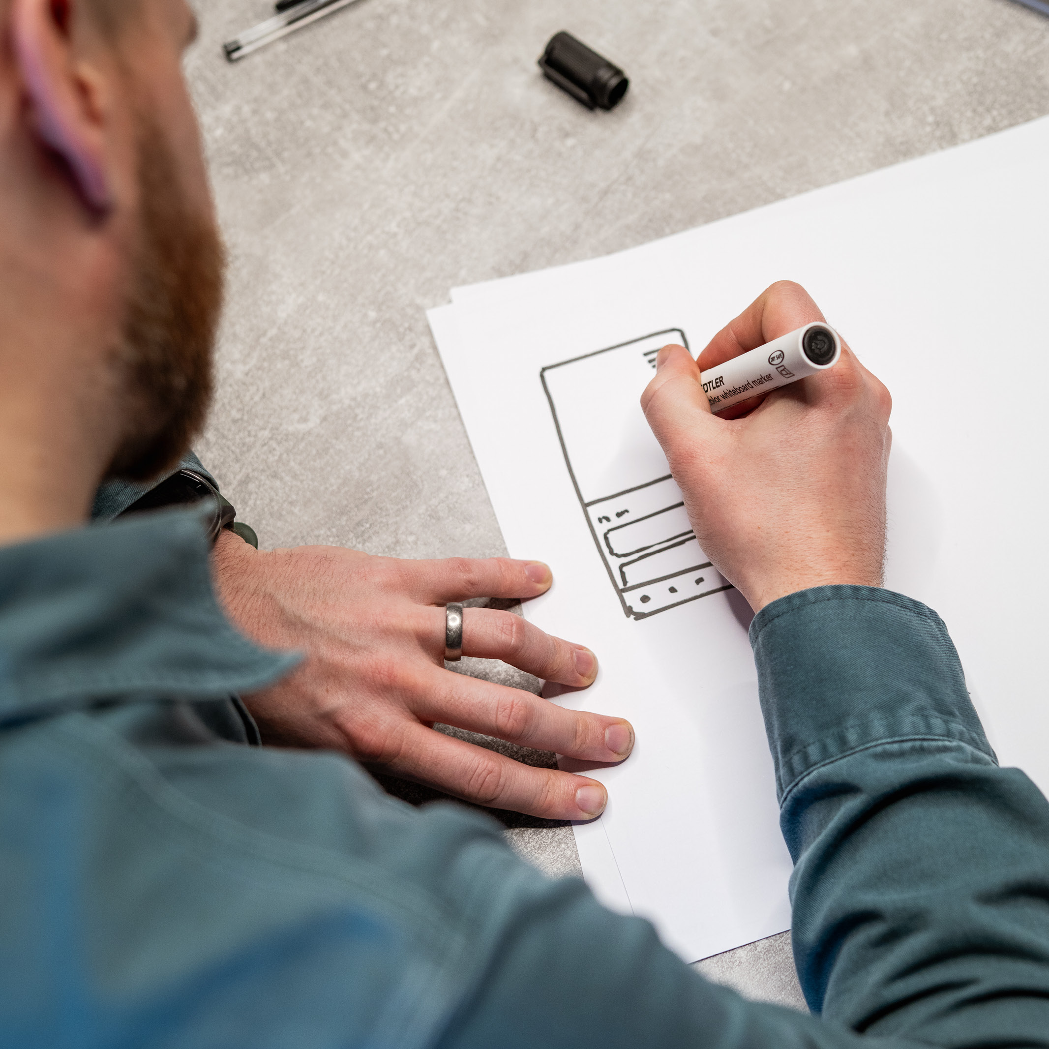A close-up of an agency creative sketching a mobile wireframe concept on paper during a Spark Day collaborative brainstorming session