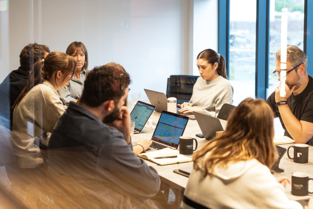 A team of marketing professionals working together around a conference table, representing full agency access and collaborative strategy.