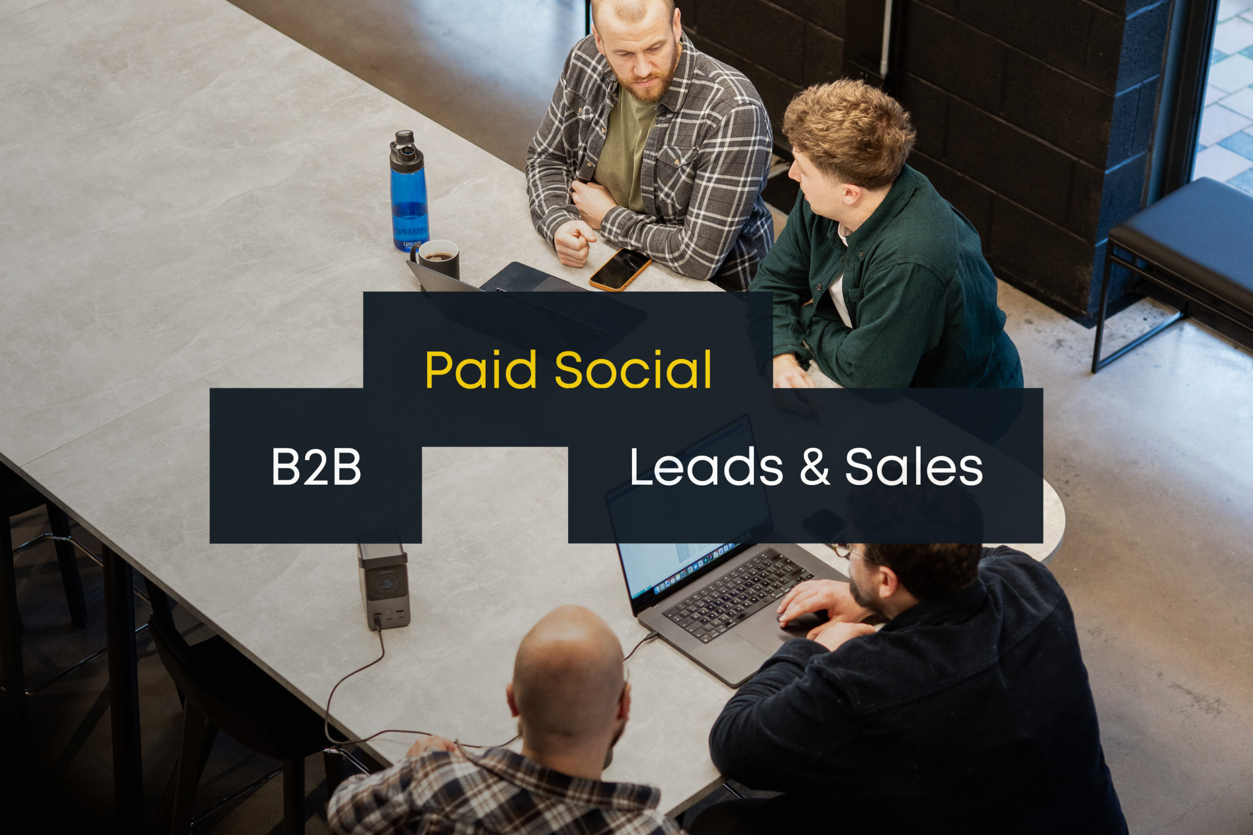 People sitting around a title discussing paid social strategies